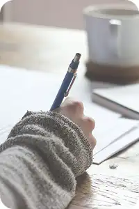 デスクの上で、美味しいカフェを添えて書き物をしている様子